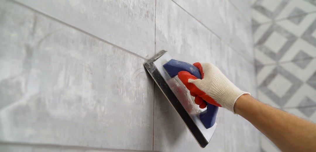 Cementsluier verwijderen van een keramische vloertegel na oplevering met spons en reiniger